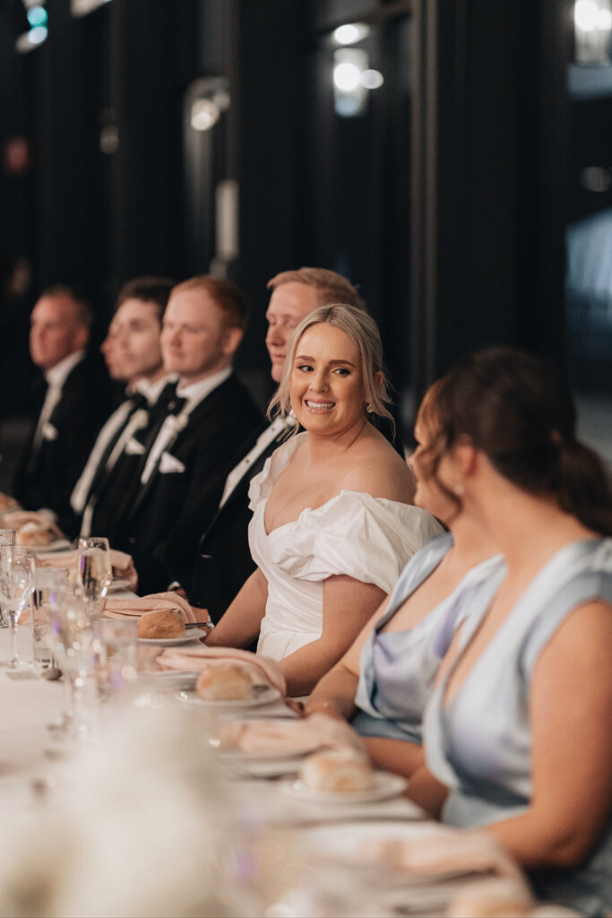 The wedding party sit together at a long table