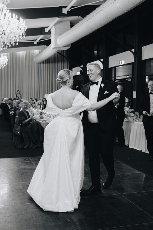 The wedding couple take their first dance on the reception's dancefloor as guests watch.
