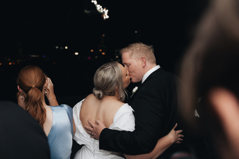 The bride and groom kiss as fireworks fill the sky