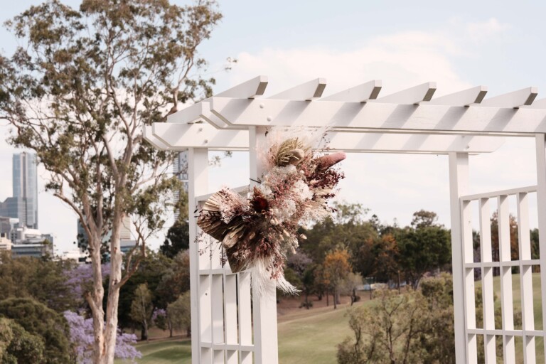 The white arbour as the alter, is adorned with florals.