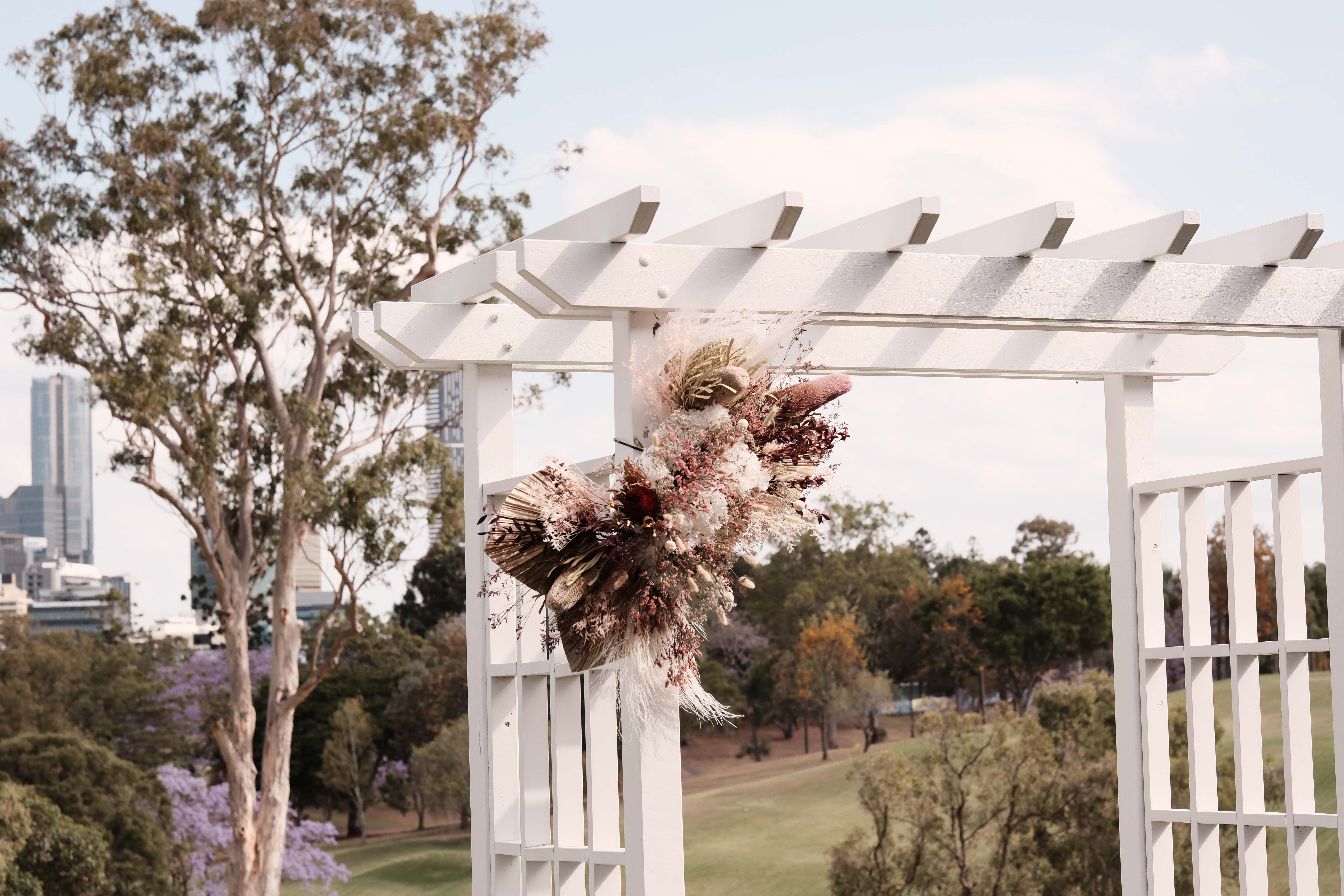 The white arbour as the alter, is adorned with florals. 