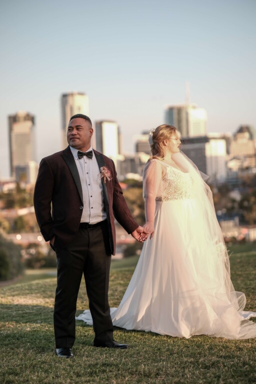 Rose and Taape stand holding stands, on a hill with the city skyline in the background.