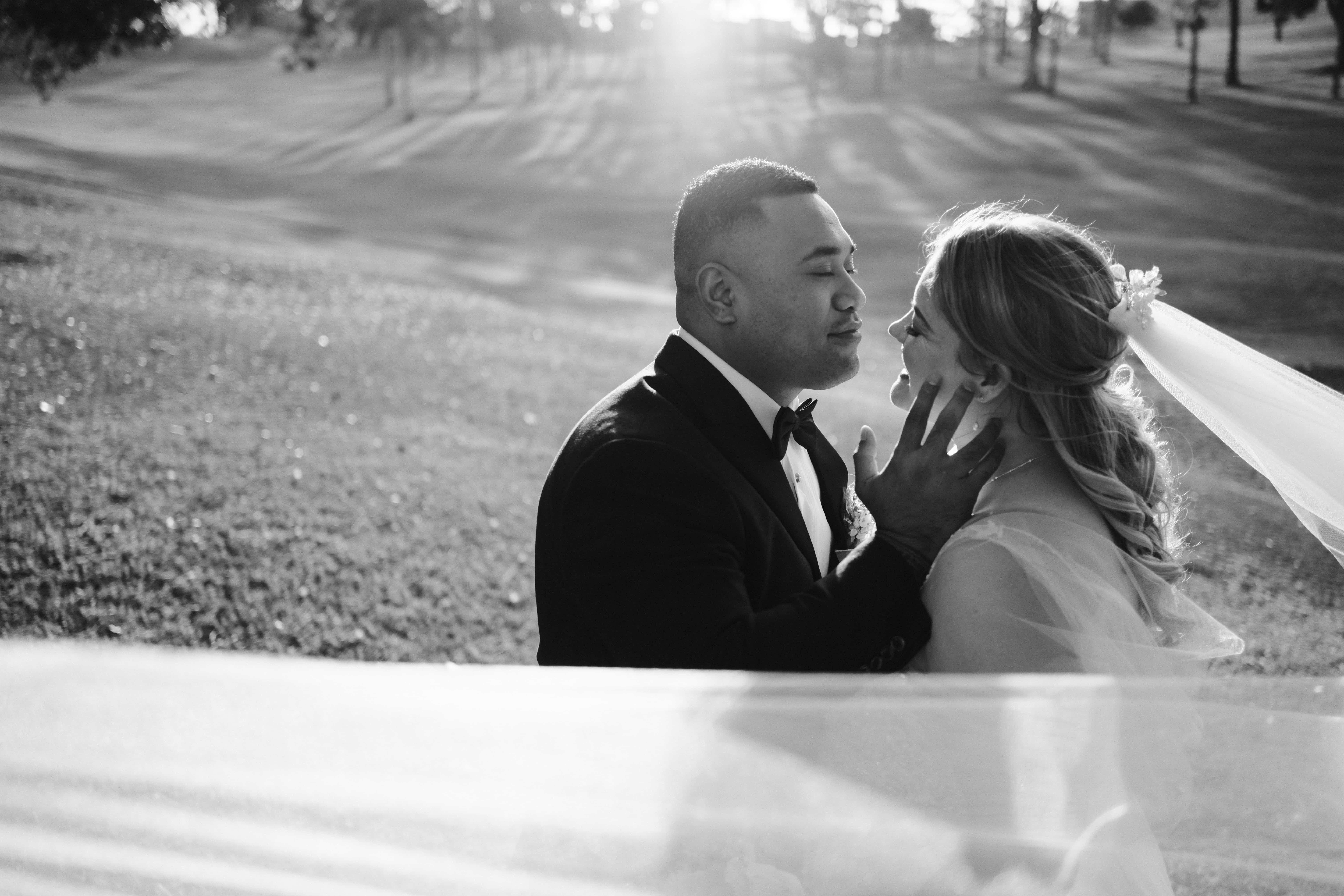 Taape and Rose romantically face each other, with Taape's hand on Rose's cheek. Rolling hills of parkland are in the background, as the sun shines through the trees.