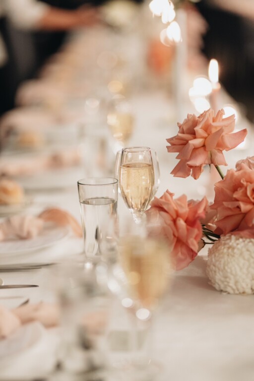 Details of the table, with peachy roses and pink napkins. Champagne glasses are filled.