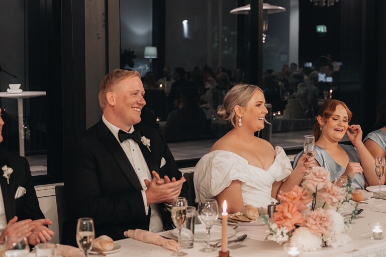 The bride and groom sit at the bridal table, as they listen to speeches.